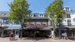 A building with a restaurant on the ground floor, a bike rack, and a pedestrian crossing. - Beautiful Well Equipped Apartment Near the Beach (Domburg)