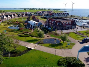 Un pueblo costero con arquitectura tradicional, un puerto deportivo y aerogeneradores.