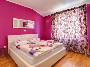 Relax in a stylish bedroom with a vibrant wall, tufted headboard, and floral-patterned bedding.