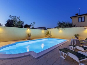 Relax by the pool surrounded by lush greenery and comfortable lounge chairs.