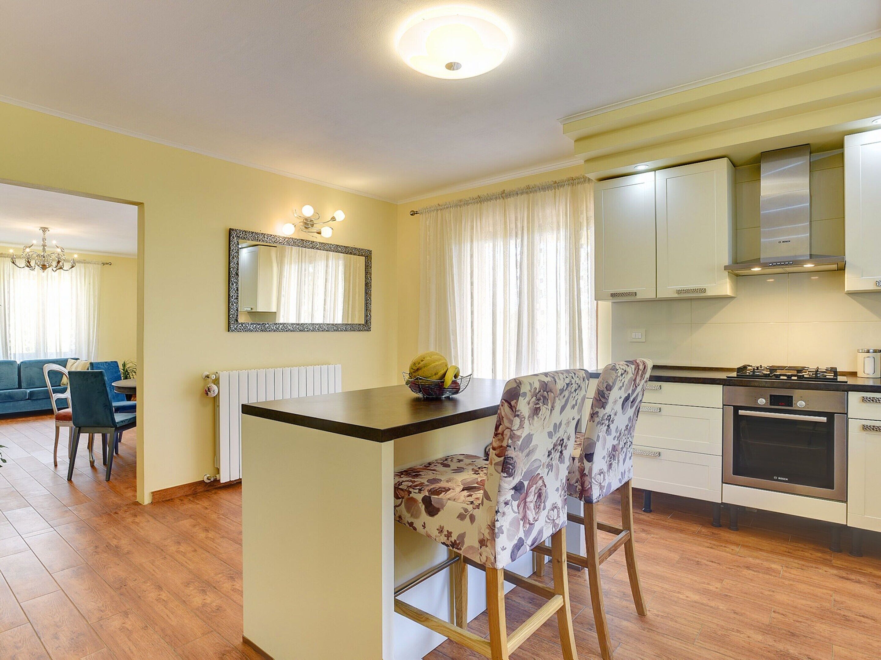 A compact kitchen with a central island, a dining area with a blue sofa, and a chandelier.