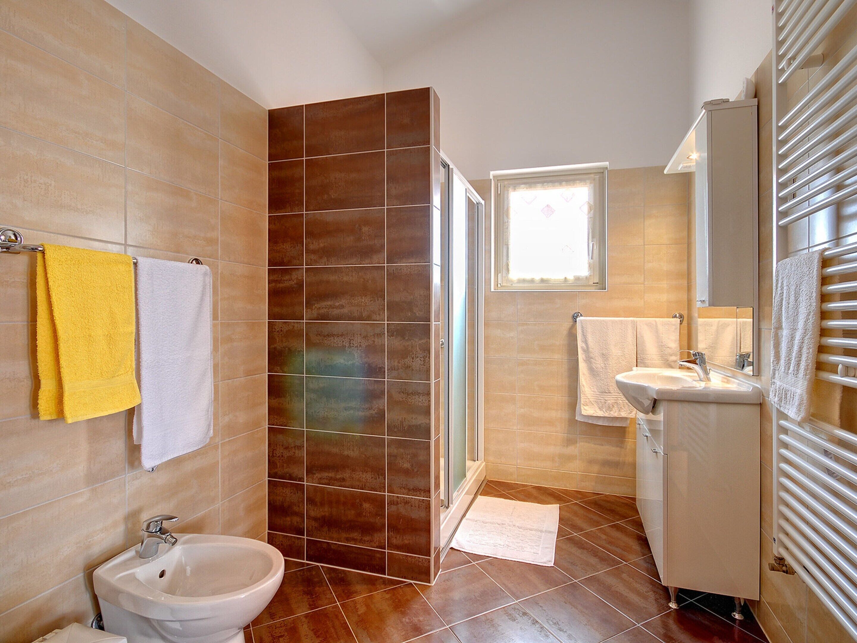 A bathroom with a bidet, a sink, a mirror, and a towel rack.