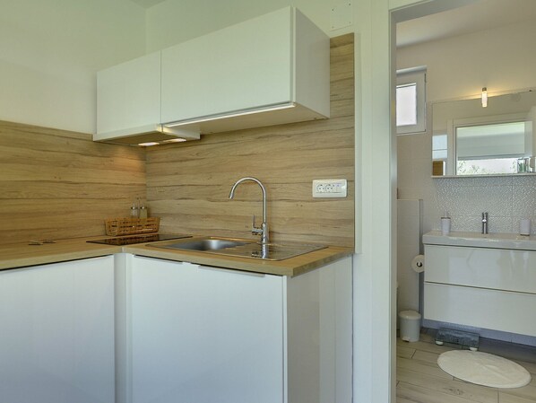 A modern kitchen with white cabinets, a stainless steel sink, and a wooden backsplash.