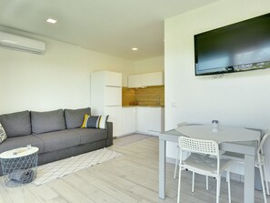 Cozy living space with a sofa, dining table, and flat-screen TV.