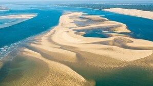 Vista aérea de un paisaje costero con dunas de arena y una masa de agua.