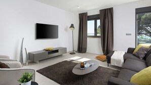 Una sala de estar moderna con un televisor de pantalla plana, un sofá gris y una mesa de centro.