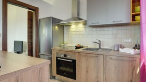 Une cuisine moderne avec des meubles en bois, des appareils électroménagers en acier inoxydable et un four encastré.