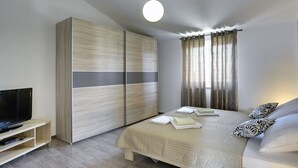 Ein modernes Schlafzimmer mit Bett, Fernseher und Kleiderschrank.