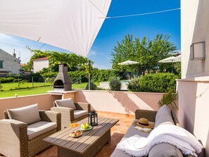 Relax in a shaded patio area with comfortable seating and outdoor cooking facilities.