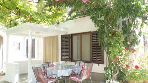 An outdoor patio with a table and chairs, surrounded by greenery and potted plants. - Lovely Apartment Near the Sea & the Center (Medulin)