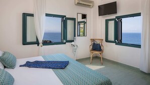 A room with two beds, a chair, a TV, and large windows overlooking the sea. - Luxury Villa With Amazing Sea Views, Private Pool, Near the Beach (Chania)