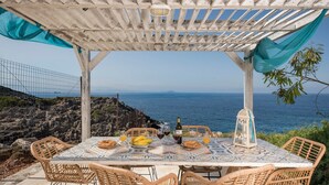 An outdoor dining area with a table set for two, overlooking the sea. - Luxury Villa With Amazing Sea Views, Private Pool, Near the Beach (Chania)