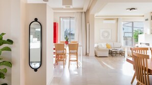 Un salón amplio con una mesa de comedor y sillas, un sofá y un espejo grande en la pared.