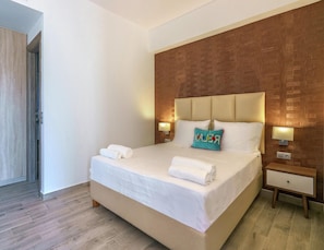 A hotel room with a large bed, two bedside tables, and a wooden accent wall.