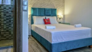 A bedroom with a teal headboard, white bedding, and a red pillow. - Villa in Plakias Near the Beach (Agios Vasileios)