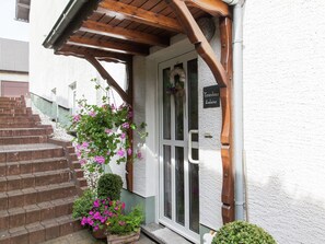 A building entrance with a wooden staircase, a hanging flower basket, and a sign reading "Ferienhaus Ludwine". - Attractive Apartment in Bettenfeld With Garden (Bettenfeld)