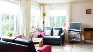 A living room with a sofa, a television, and a small table. - Attractive Apartment in Bettenfeld With Garden (Bettenfeld)