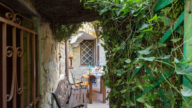 Une ruelle étroite avec un banc, une table sur laquelle sont posés divers objets, et un bâtiment doté d’une fenêtre et d’une porte.