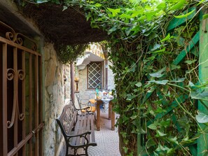 Une ruelle étroite avec un banc, une table sur laquelle sont posés divers objets, et un bâtiment doté d’une fenêtre et d’une porte.