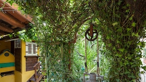 Un espace extérieur rustique agrémenté d’une cabane en bois, d’une fontaine en métal et d’une végétation luxuriante.