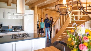 A modern kitchen with white cabinets, a central island, and a gas stove. - Luxury Villa in the Achterhoek (Lochem)