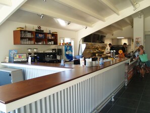 Una cucina moderna con un lungo bancone, macchine da caffè e diversi elettrodomestici.