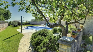 A swimming pool surrounded by stone walls, a grassy lawn, and various plants. - Holiday Home Vodnjan With Private Pool (Marcana)