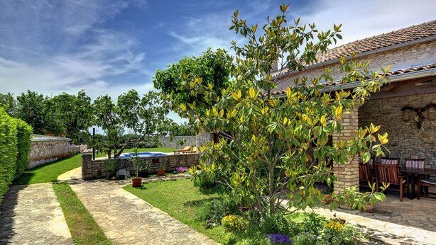A stone pathway leading to a stone building with a tiled roof, surrounded by lush greenery and flowering plants. - Holiday Home Vodnjan With Private Pool (Marcana)
