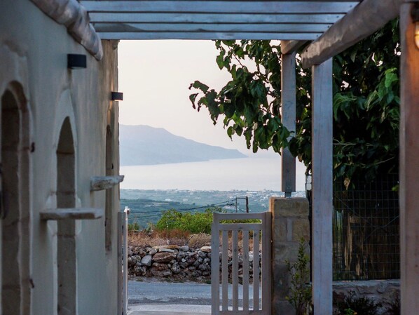 A stone gate leading to a view of a body of water and mountains.