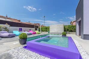 A rooftop pool area with a rectangular pool, surrounded by colorful lounge chairs and potted plants. - Holiday Home in Pula Near Beach (Pula)