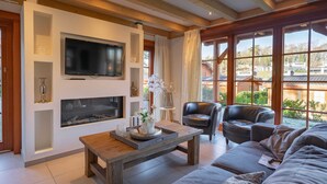 Un salon moderne doté d’une cheminée, d’un téléviseur et d’une grande fenêtre donnant sur l’extérieur.