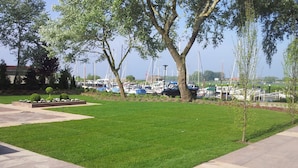 A well-maintained grassy area with a paved walkway, surrounded by trees and a marina with boats. - Modern Chalet With Dishwasher Near Biesbosch (Dordrecht)