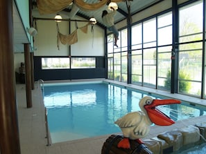 An indoor swimming pool with a large window, a lifeguard stand, and a decorative bird statue. - Modern Chalet With Dishwasher Near Biesbosch (Dordrecht)