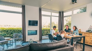 A modern dining area with a large window, a flat-screen TV, and a dining table with chairs.