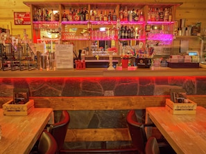 A bar area with multiple shelves of liquor bottles, a menu board, and a wooden counter. - Modern Chalet Near Brunssummerheide (Brunssum)