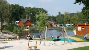 Un parc au bord du lac, équipé de balançoires, de tables de pique-nique et d’une aire de jeux.