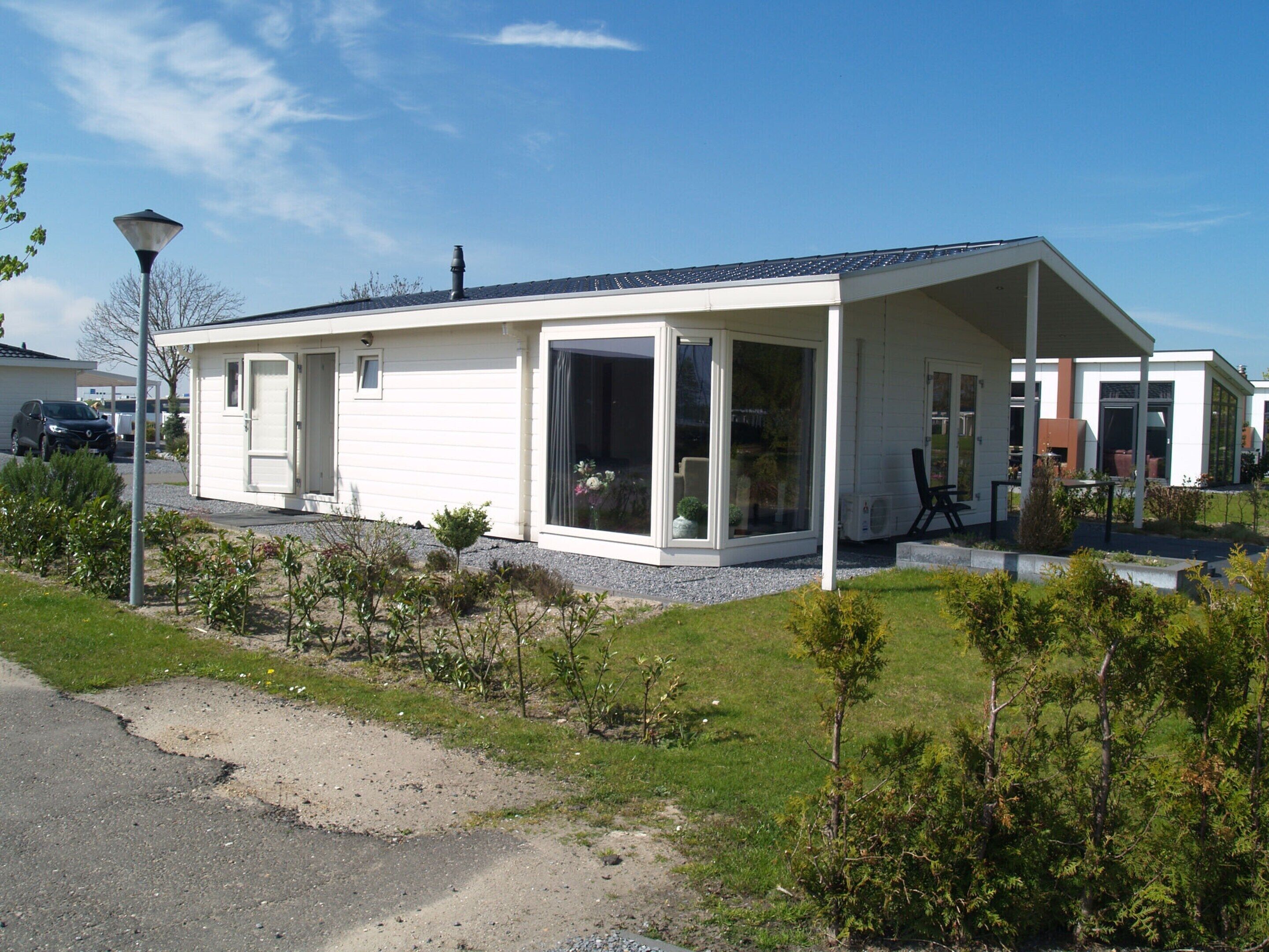 Una casa moderna a un piano con portico coperto, ampie finestre e garage.
