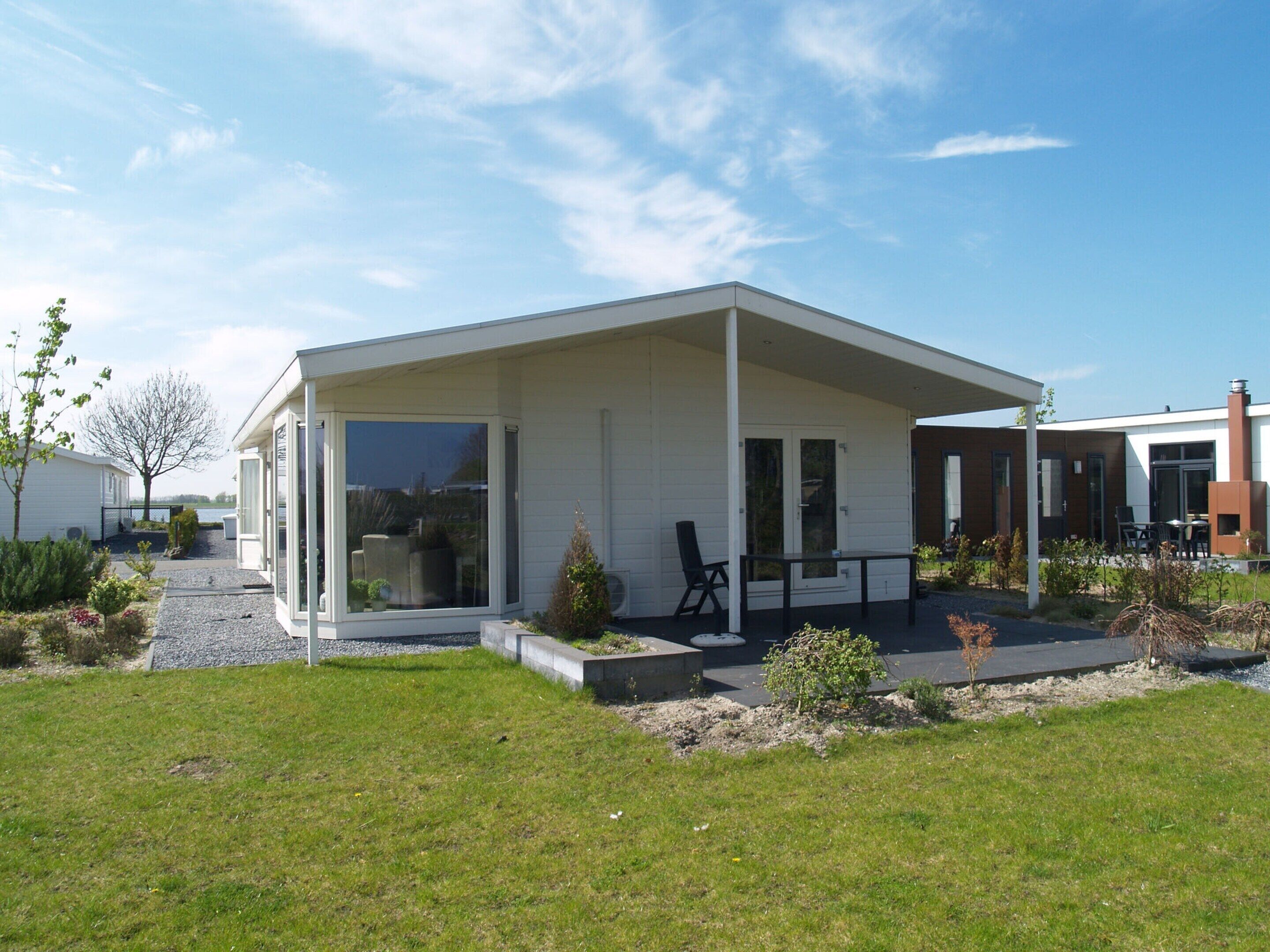 Una casa moderna con patio coperto, un piccolo giardino e vista sull'acqua.