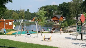 Un parc au bord du lac, équipé de balançoires, d’une aire de jeux et d’un espace pique-nique.