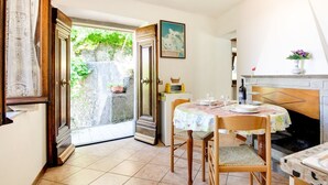 A dining area with a table set for four, a fireplace, and a view of greenery outside. - Farmhouse in Casoli Near Ski Slopes (Bagni di Lucca)