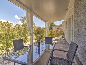 An outdoor patio with wicker chairs, a glass table, and a bottle of wine. - Mobile Home in Banjole Near Beach & Pool (Medulin)
