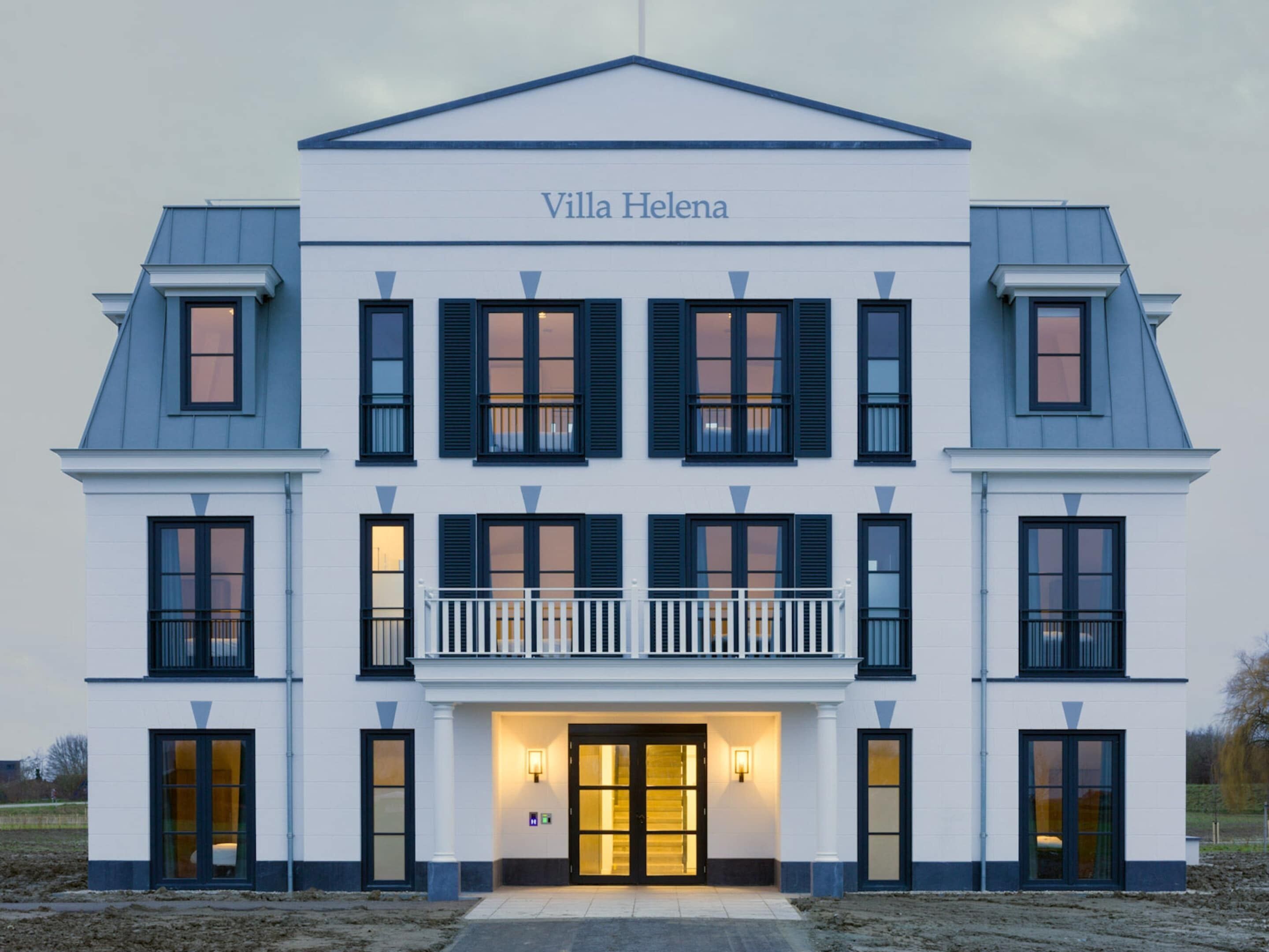 Un edificio de dos pisos llamado Villa Helena con una fachada simétrica, múltiples ventanas con contraventanas y una entrada central con una lámpara.