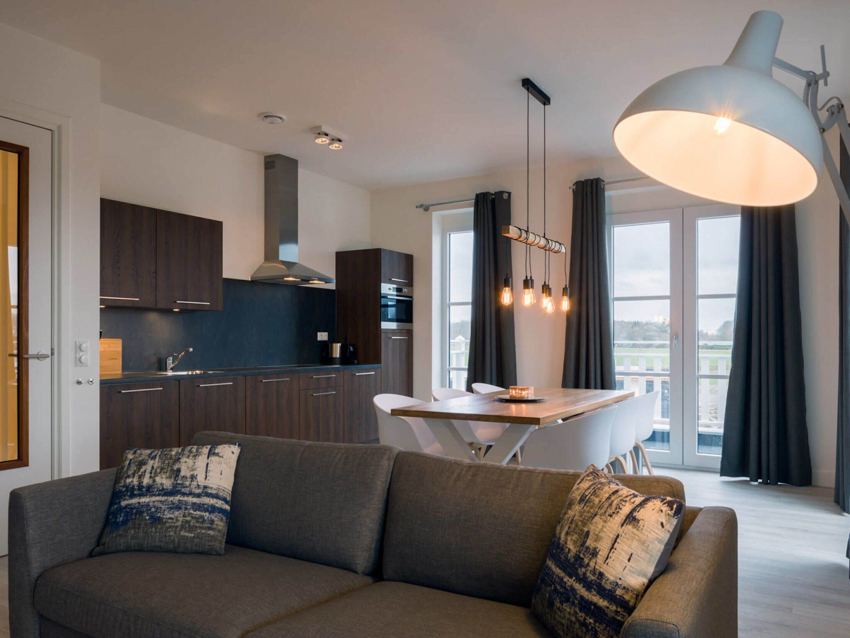 A modern kitchen with dark cabinets, a central island, and pendant lighting.