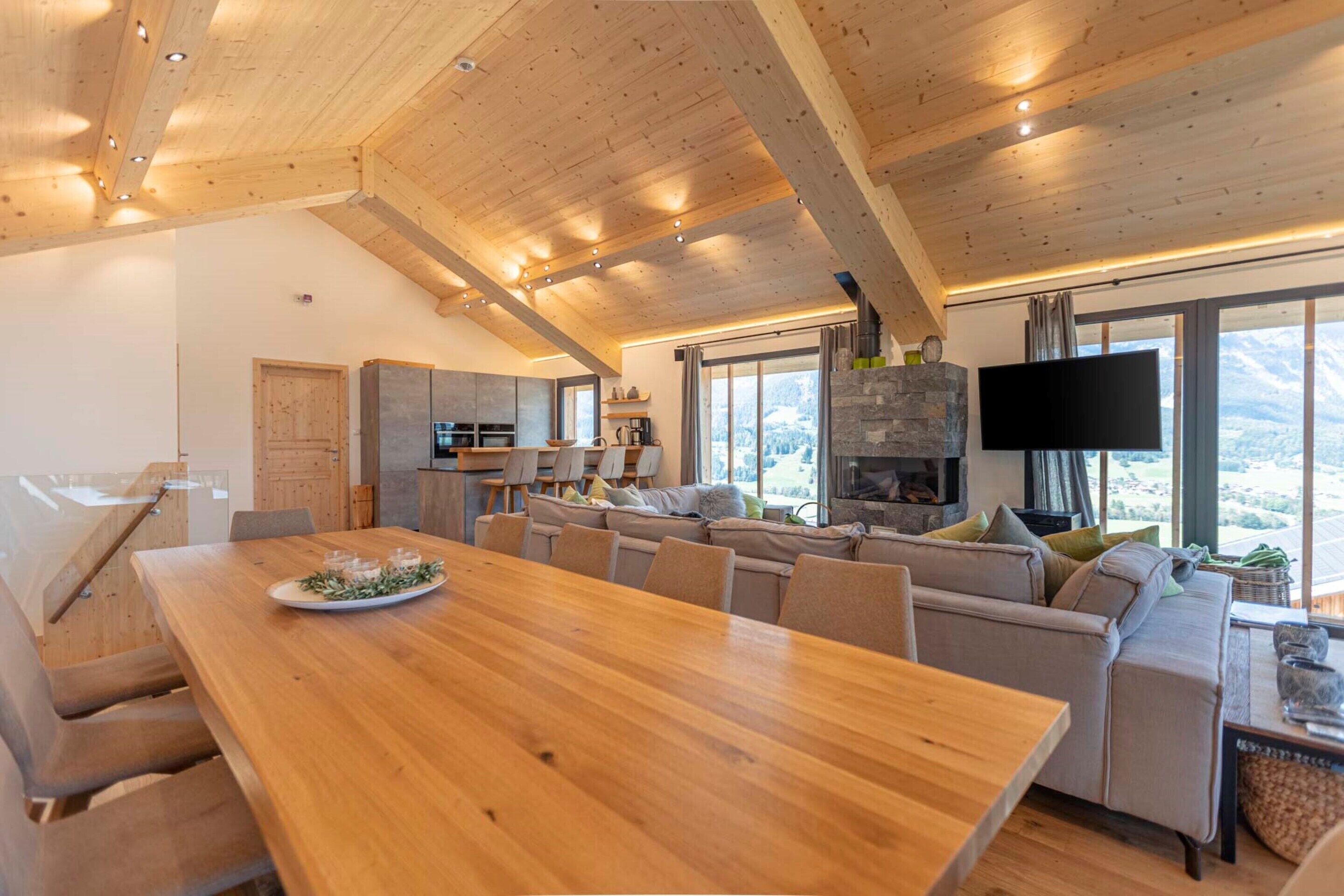 A spacious living area with a wooden ceiling, a large dining table, and a sofa.