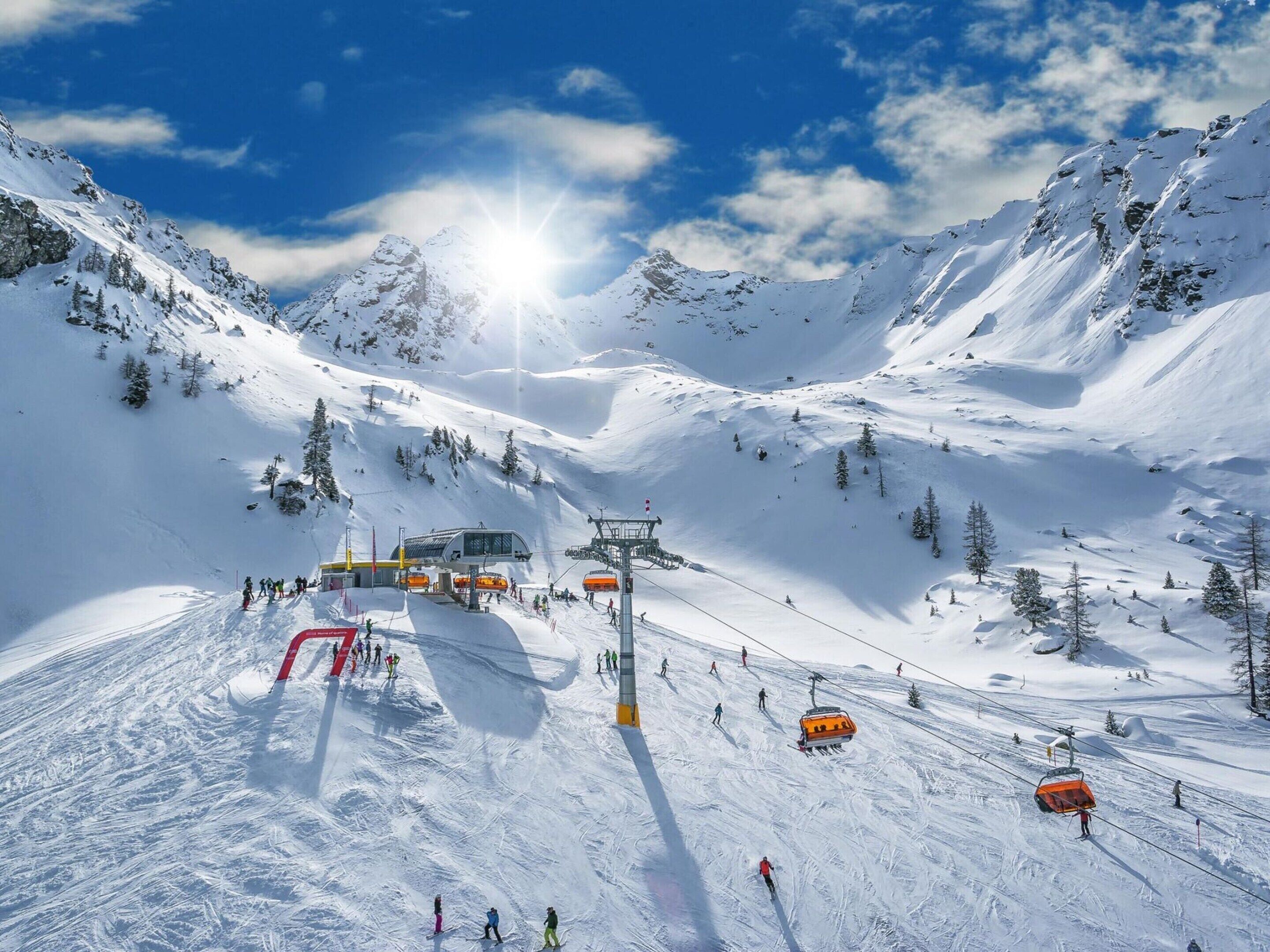 A snow-covered mountain with a ski lift and skiers.
