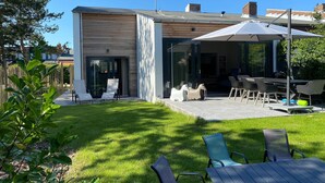 A modern house with a patio, outdoor seating, and a covered area. - Holiday Home Nieuwvliet Near Beach (Nieuwvliet)