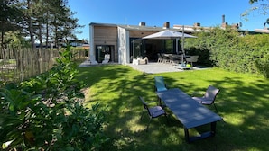 A modern house with a patio, outdoor seating, and a fenced yard. - Holiday Home Nieuwvliet Near Beach (Nieuwvliet)