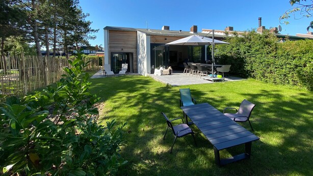 A modern house with a patio, outdoor seating, and a fenced yard. - Holiday Home Nieuwvliet Near Beach (Nieuwvliet)