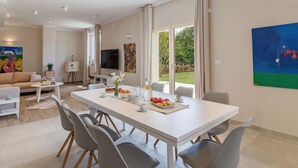 Ein modernes Wohnzimmer mit Essbereich, einer Couch, einem Fernseher und Kunstwerken an den Wänden.