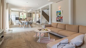 Ein großzügiger Wohnbereich mit Sofa, einem Esstisch und einer Küche im Hintergrund.
